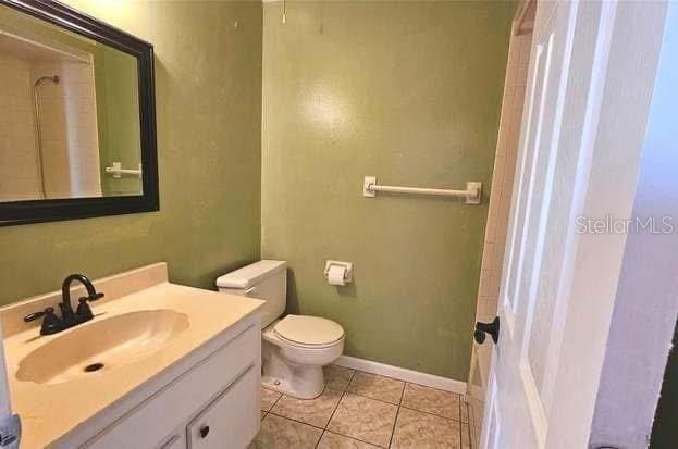 bathroom featuring vanity, toilet, tile patterned flooring, and a shower