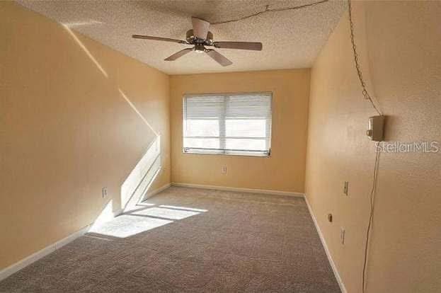 carpeted empty room with ceiling fan and a textured ceiling