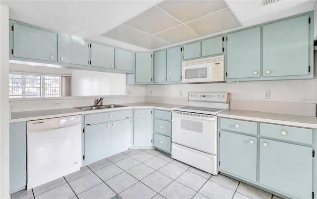 kitchen with light tile patterned floors, white appliances, and sink