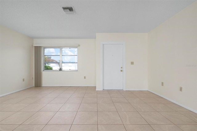 unfurnished room featuring a textured ceiling and light tile patterned flooring