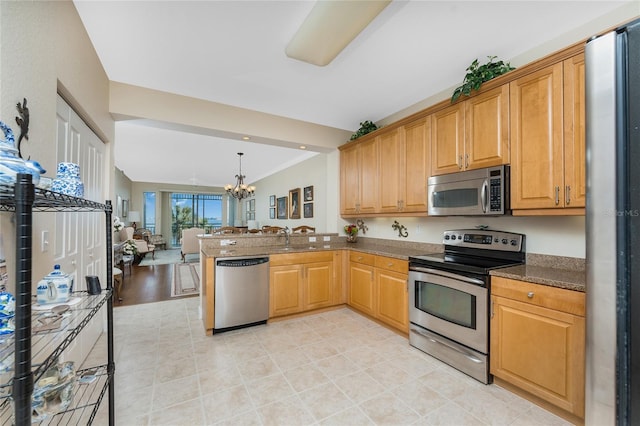 kitchen featuring an inviting chandelier, sink, hanging light fixtures, kitchen peninsula, and stainless steel appliances