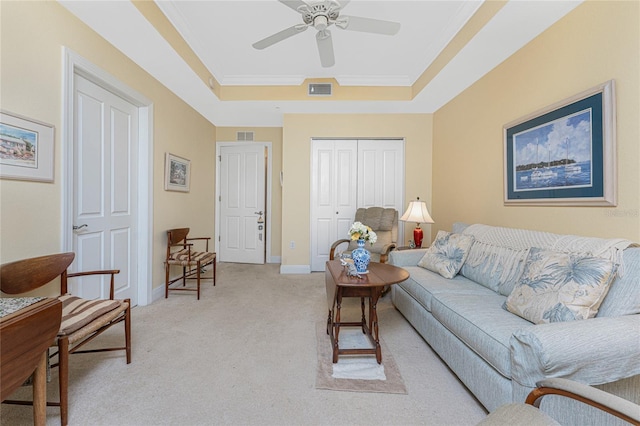 living room with light carpet, a tray ceiling, ceiling fan, and ornamental molding