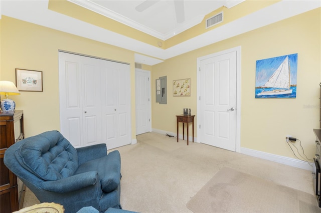 living area with a tray ceiling, ceiling fan, light colored carpet, and ornamental molding