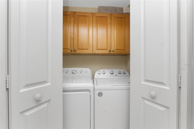 laundry room with washing machine and clothes dryer and cabinets