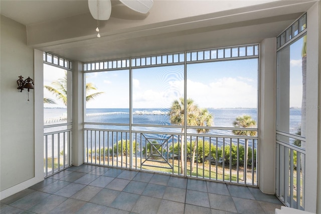 unfurnished sunroom with ceiling fan, plenty of natural light, and a water view