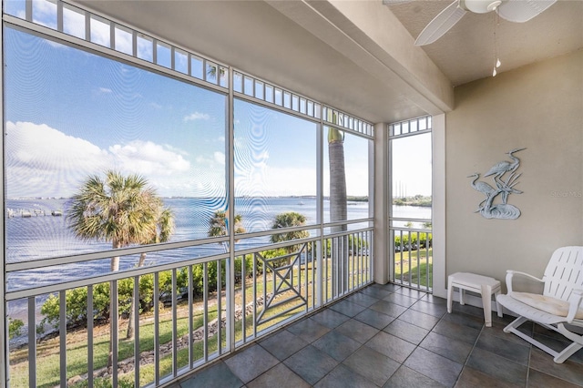 sunroom / solarium featuring ceiling fan and a water view