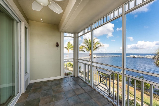 unfurnished sunroom featuring ceiling fan and a water view