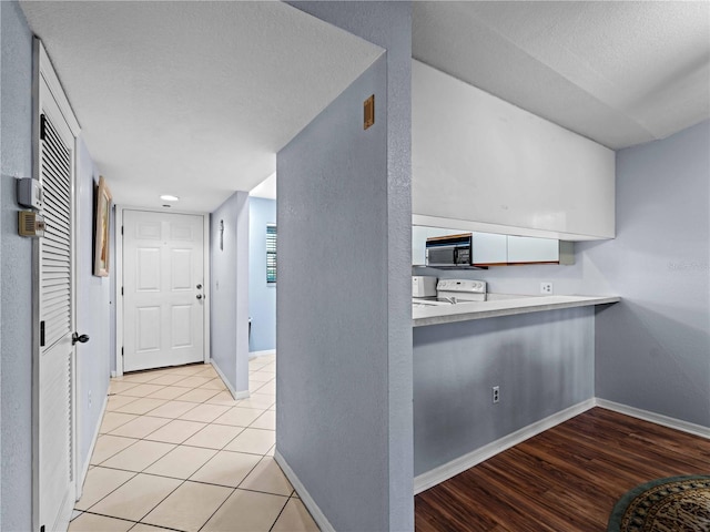 kitchen featuring a textured ceiling, white cabinets, light tile patterned floors, and white electric stove