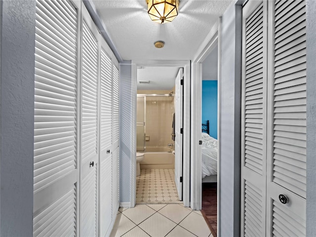 hallway featuring a textured ceiling and light tile patterned flooring