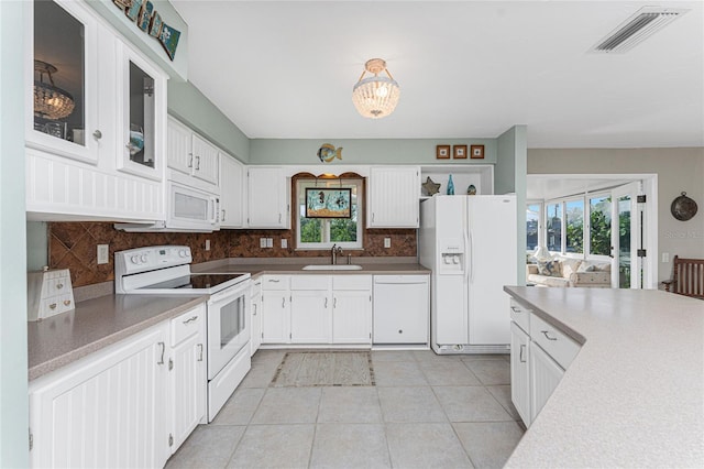 kitchen with decorative backsplash, white appliances, a healthy amount of sunlight, sink, and white cabinets