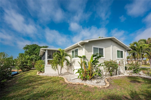 view of side of home with a sunroom and a yard