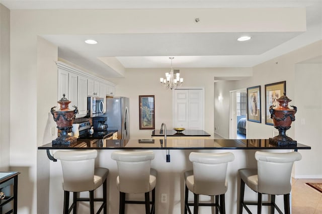 kitchen with white cabinets, a kitchen breakfast bar, kitchen peninsula, and appliances with stainless steel finishes