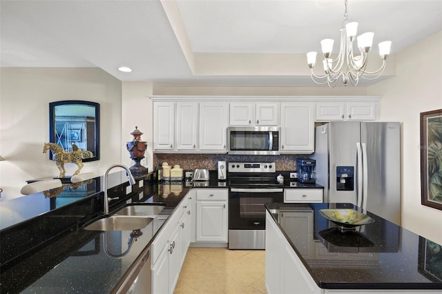 kitchen with white cabinetry, sink, stainless steel appliances, dark stone countertops, and a chandelier