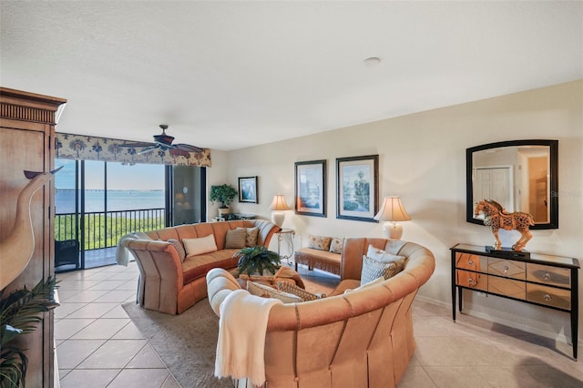 living room featuring ceiling fan, a water view, and light tile patterned floors