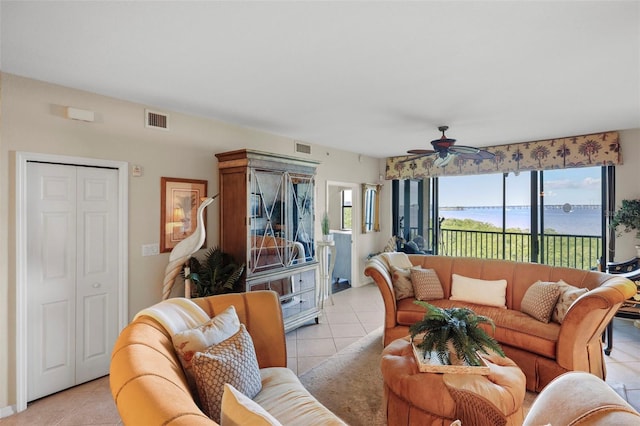 tiled living room with ceiling fan and a water view