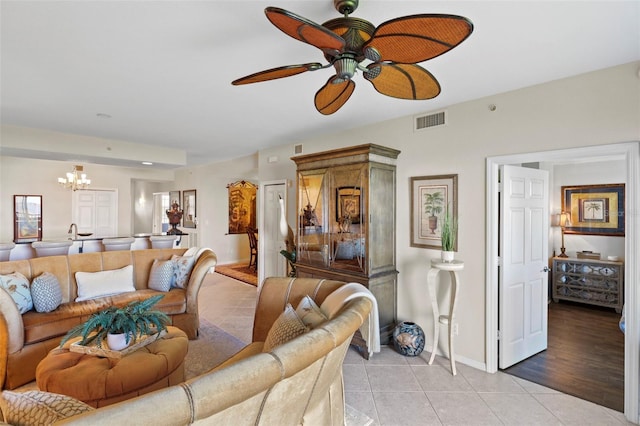 living room with light tile patterned flooring and ceiling fan with notable chandelier