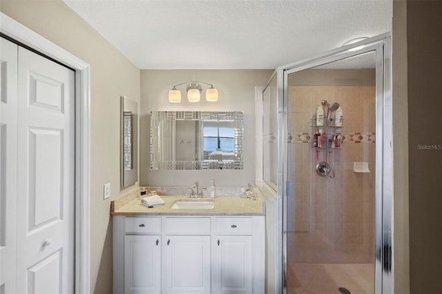 bathroom with a textured ceiling, vanity, and walk in shower