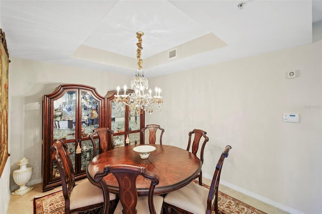 tiled dining room with a raised ceiling and an inviting chandelier