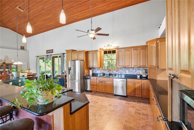 kitchen featuring a kitchen bar, tasteful backsplash, stainless steel appliances, high vaulted ceiling, and a center island