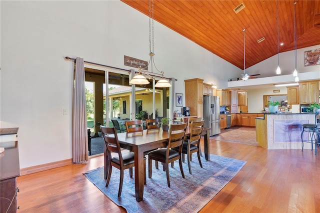 dining space featuring ceiling fan, light hardwood / wood-style floors, wood ceiling, and a high ceiling