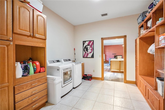 washroom with cabinets, light tile patterned floors, and washing machine and clothes dryer