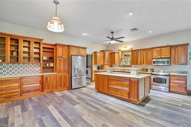 kitchen with stainless steel appliances, ceiling fan, decorative light fixtures, light hardwood / wood-style flooring, and a kitchen island