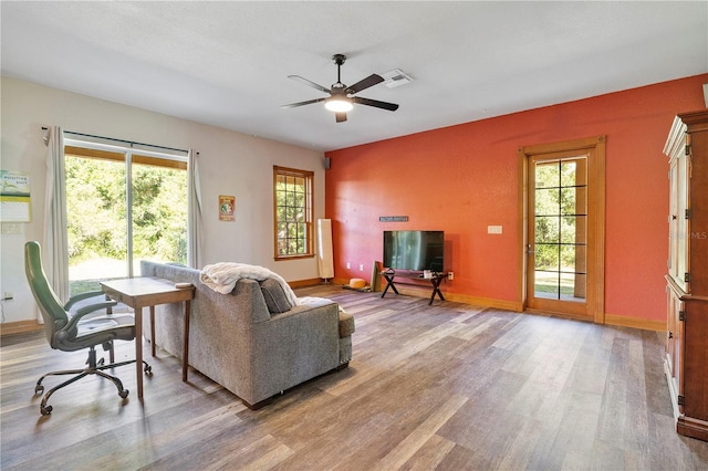 living room featuring ceiling fan, plenty of natural light, and wood-type flooring