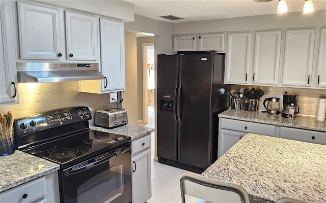 kitchen with white cabinetry, light stone countertops, tasteful backsplash, extractor fan, and black appliances