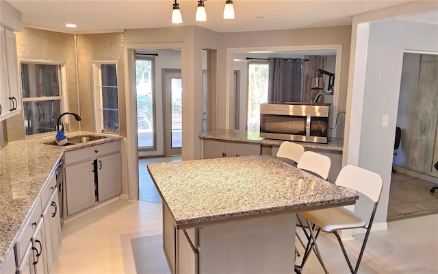 kitchen with a breakfast bar area, a center island, hanging light fixtures, and sink