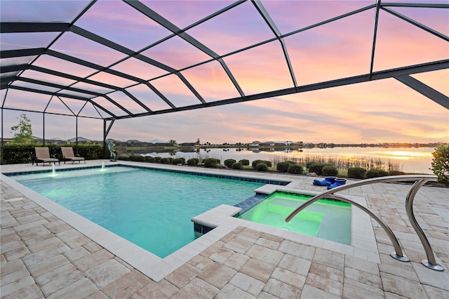 pool at dusk featuring an in ground hot tub, pool water feature, a water view, glass enclosure, and a patio