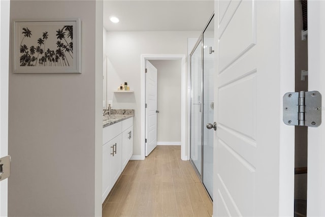 corridor with light hardwood / wood-style flooring and sink