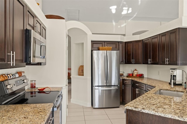 kitchen featuring dark brown cabinetry, light stone countertops, sink, and appliances with stainless steel finishes