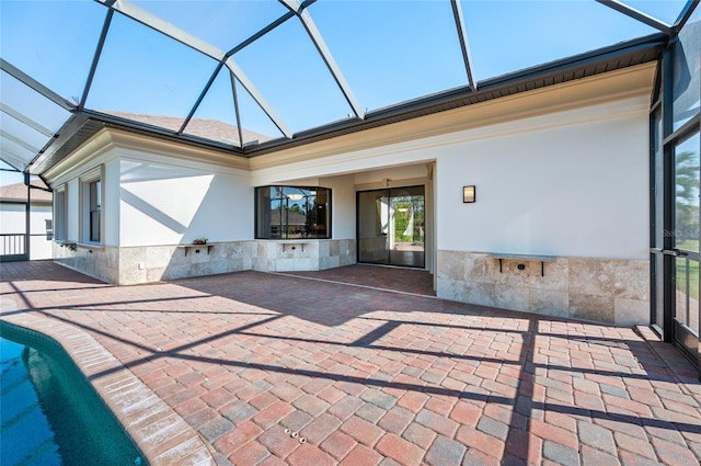 rear view of property with glass enclosure and a patio