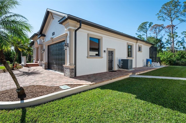 rear view of property with a garage, a lawn, and central air condition unit