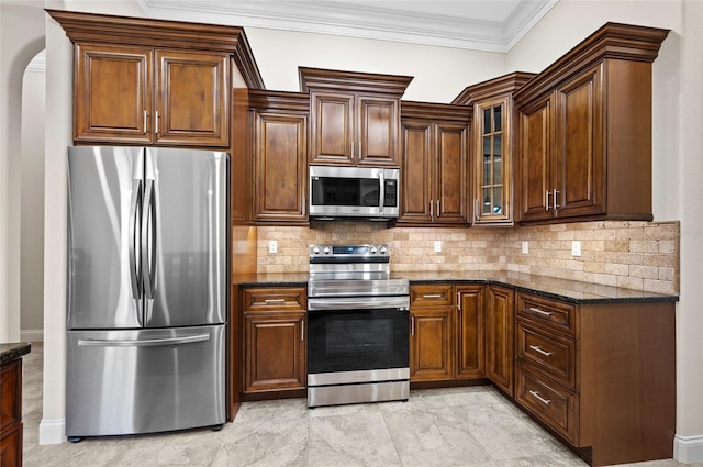 kitchen featuring backsplash, ornamental molding, stainless steel appliances, and dark stone counters