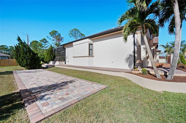 view of home's exterior with a lanai, a patio area, and a yard