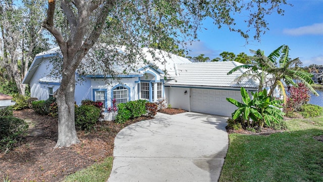 single story home with an attached garage, a tile roof, concrete driveway, and stucco siding