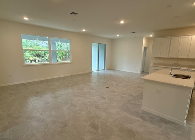 interior space with recessed lighting, a sink, visible vents, and baseboards