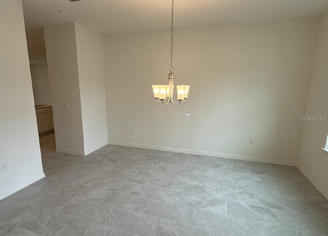 spare room with baseboards and a notable chandelier