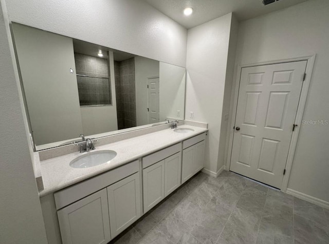 full bathroom featuring a walk in shower, a sink, baseboards, and double vanity