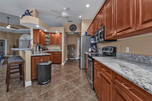 kitchen featuring sink, ceiling fan, a kitchen bar, and stainless steel appliances