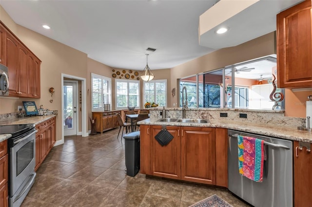 kitchen featuring light stone countertops, appliances with stainless steel finishes, ceiling fan, sink, and pendant lighting