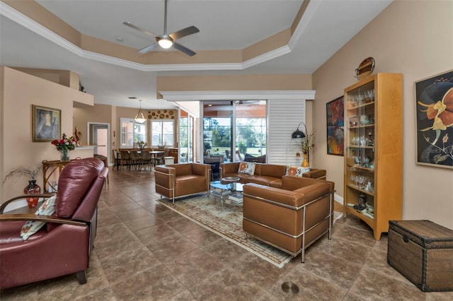 living room with a raised ceiling, ceiling fan, and ornamental molding