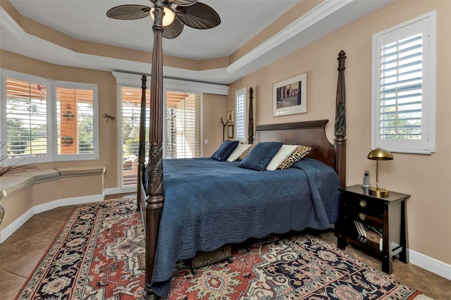 tiled bedroom featuring multiple windows, a raised ceiling, and ceiling fan