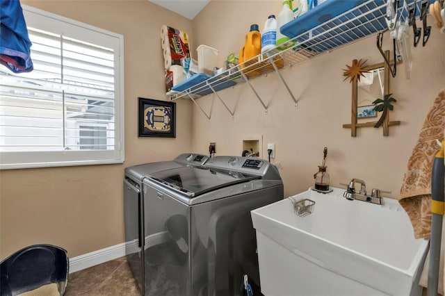 washroom featuring washing machine and dryer, dark tile patterned flooring, and sink