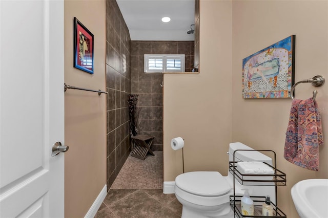 bathroom featuring tile patterned floors, a tile shower, and toilet