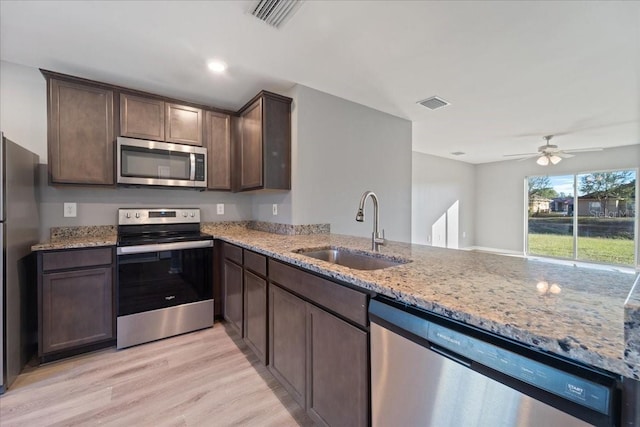 kitchen featuring sink, ceiling fan, light stone countertops, light wood-type flooring, and stainless steel appliances