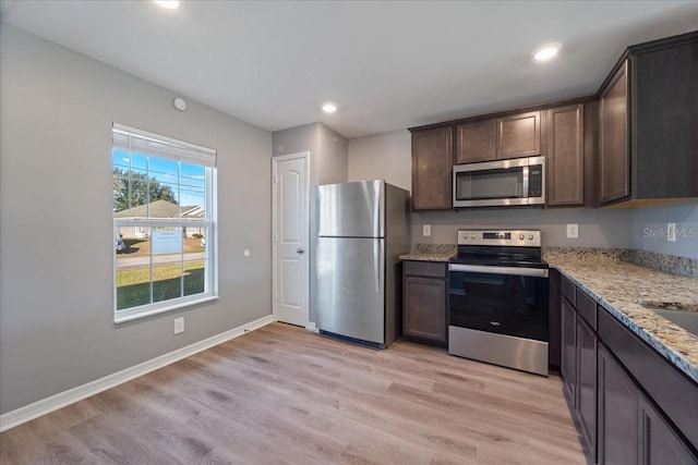 kitchen featuring light hardwood / wood-style floors, light stone counters, dark brown cabinetry, and stainless steel appliances