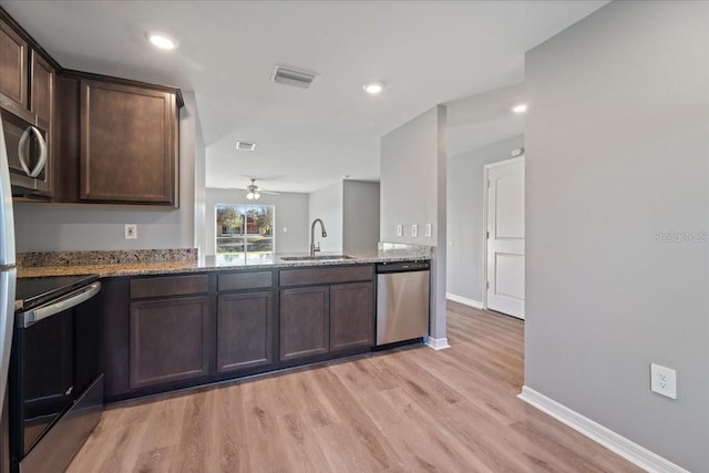 kitchen featuring sink, light stone counters, dark brown cabinets, appliances with stainless steel finishes, and light wood-type flooring