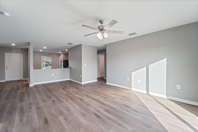 unfurnished living room featuring ceiling fan and light hardwood / wood-style flooring